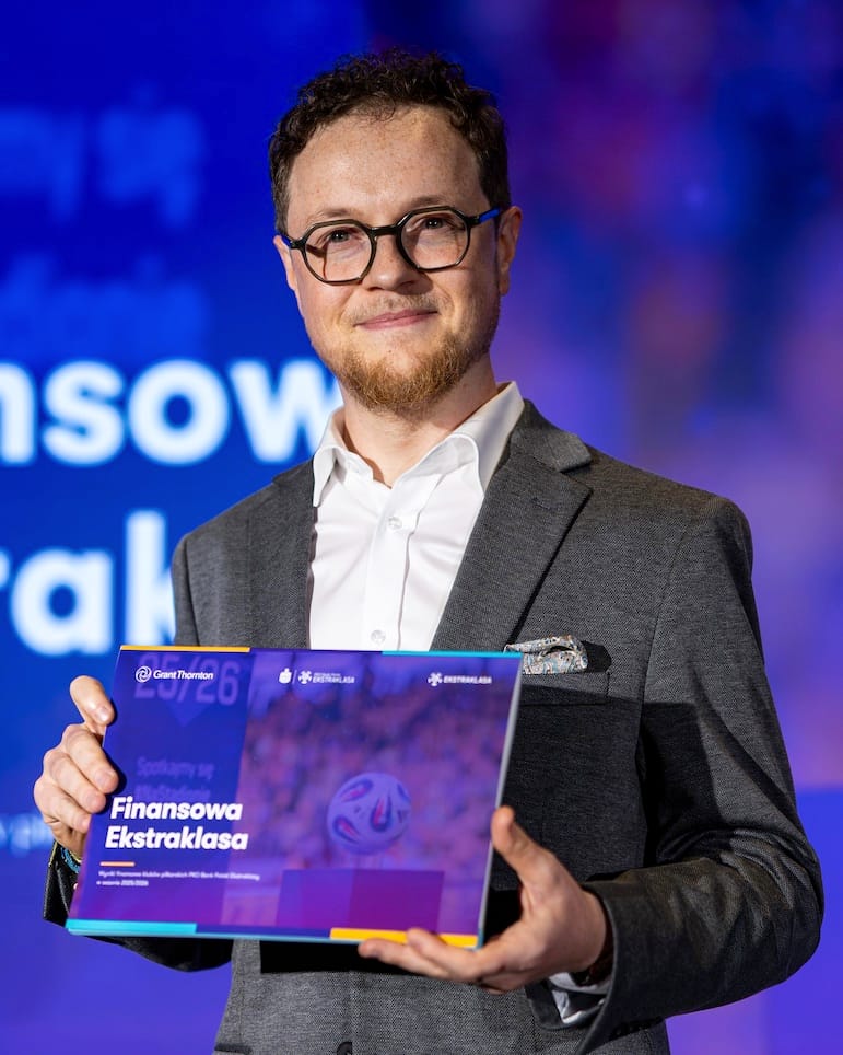 Wojciech Olszewski na scenie z wydrukowanym raportem „Finansowa Ekstraklasa” za sezon 2025/26
